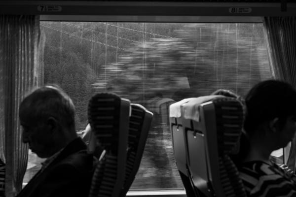 Silhouettes on a train with a blurry and rainy world passing by outside